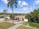 Inviting single-story home featuring a driveway, mature palm trees, and partial water view at 1730 Sunset Point Rd, Clearwater, FL 33755