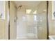 Walk-in shower with clear glass door and tan tile, featuring a shower head and grab bar at 1730 Sunset Point Rd, Clearwater, FL 33755