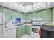 Functional kitchen with white tile floors, green cabinets, and ample counter space at 19029 Us Highway 19 N # 8-15, Clearwater, FL 33764