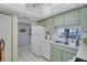 Efficient kitchen layout with white appliances, green cabinets, and access to living area at 19029 Us Highway 19 N # 8-15, Clearwater, FL 33764
