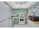 Cozy kitchen featuring retro green cabinets, white appliances, and tile flooring at 19029 Us Highway 19 N # 8-15, Clearwater, FL 33764