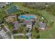 Stunning aerial view of community pool, playground, lake, and clubhouse surrounded by lush landscaping and swaying palm trees at 35583 Burma Reed Dr, Zephyrhills, FL 33541