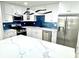 Modern kitchen boasts an island with quartz countertop, stainless appliances, stylish lighting and blue backsplash at 3735 69Th N Way, St Petersburg, FL 33710