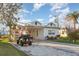 Lovely exterior view of a home with a well-kept lawn, driveway, and a golf cart parked nearby at 607 Manatee Ave, Ellenton, FL 34222