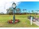 Scenic putting green with colorful flowers, palm trees, and bike rack against a blue sky at 6325 Stone River Rd, Bradenton, FL 34203