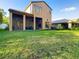A shot of the backyard showing the house, covered patio, and green grass at 8264 Dunham Station Dr, Tampa, FL 33647