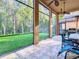 Covered patio with ceiling fans and tile floors overlooks the green backyard and a beautiful line of trees at 8264 Dunham Station Dr, Tampa, FL 33647