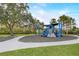 Community playground featuring shaded play structure with slides, walkways, and bench sitting in green space and walking paths at 8264 Dunham Station Dr, Tampa, FL 33647