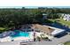 Aerial view of community featuring a pool, adjacent clubhouse, mature trees, and serene pond with fountain at 960 Virginia St # 205, Dunedin, FL 34698