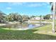 A full view of the pond from ground level, showcasing lush grass and the surrounding community buildings at 960 Virginia St # 205, Dunedin, FL 34698