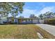 Charming single-story home with blue exterior, a well-maintained yard and a brick-paved driveway at 1101 Jackmar Rd, Dunedin, FL 34698