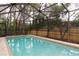 Screened-in pool featuring a clean interior, concrete perimeter, and a wood fence surround at 13305 Whitby Rd, Hudson, FL 34667