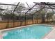 Screened-in pool featuring a clean interior, concrete perimeter, and a wood fence surround at 13305 Whitby Rd, Hudson, FL 34667