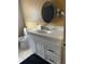 Bathroom featuring a white vanity with sleek black hardware and a round mirror at 1579 Magnolia Dr, Clearwater, FL 33756
