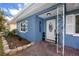 Inviting covered porch with charming decor and well-manicured landscaping by the front door at 1579 Magnolia Dr, Clearwater, FL 33756