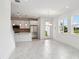 Open-concept living area with sleek flooring and a view of the modern kitchen with stainless appliances at 31857 Anchor Point Dr, Wesley Chapel, FL 33545