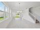 Bright living room features large windows, elegant chandelier, white walls, and marble-style tile flooring at 31857 Anchor Point Dr, Wesley Chapel, FL 33545