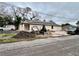 View of a home with an excavator in the front yard and construction vehicles in the background on a cloudy day at 3413 N 72Nd St, Tampa, FL 33619
