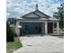 View of charming beige single-story home with a red front door and a two-car garage with a concrete driveway at 3413 N 72Nd St, Tampa, FL 33619