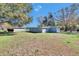 Large backyard view showcasing the home's exterior, lawn, and a storage shed at 39809 Pretty Pond Rd, Zephyrhills, FL 33540