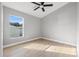 Bright bedroom with wood-look floors, grey walls, a ceiling fan, and a large window at 6449 Woodland Ln, New Port Richey, FL 34653