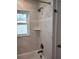 Bright shower showcasing marble-style tile, a shower head, and a corner storage shelf at 675 Marjon Ave, Dunedin, FL 34698