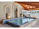 Bright indoor pool area featuring neutral tiling, a wood beam ceiling, three arches, two water features, and elegant decor at 732 Oak Ne St, St Petersburg, FL 33701