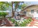 A backyard with a stone patio featuring outdoor seating and a dining area, surrounded by landscaping and a well-maintained fence at 907 E Hamilton Ave, Tampa, FL 33604