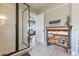 Well-lit bathroom featuring a glass-enclosed shower, tiled floors, and a decorative cabinet for storage and towels at 907 E Hamilton Ave, Tampa, FL 33604