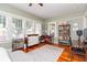 Sunlit bedroom featuring hardwood floors, neutral walls, multiple windows, and space for a desk and shelving at 907 E Hamilton Ave, Tampa, FL 33604