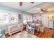 Bright bedroom features hardwood floors, multiple windows, comfortable sofa, and a crib at 907 E Hamilton Ave, Tampa, FL 33604