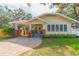 Charming yellow bungalow featuring brick accents, a covered porch, and mature landscaping, all nestled under shady trees at 907 E Hamilton Ave, Tampa, FL 33604