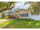 Charming yellow home featuring a welcoming front porch, lush lawn, and mature trees at 907 E Hamilton Ave, Tampa, FL 33604