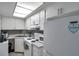 Bright kitchen featuring white cabinets, gray backsplash, and modern appliances at 100 Waverly Way # 101, Clearwater, FL 33756