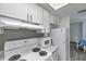 Kitchen featuring white cabinets, gray backsplash, and modern appliances at 100 Waverly Way # 101, Clearwater, FL 33756