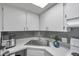 Bright kitchen featuring white cabinets, gray backsplash, and modern appliances at 100 Waverly Way # 101, Clearwater, FL 33756