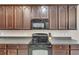Close up of kitchen featuring dark wood cabinets, black appliances, and stone countertops at 10328 Celtic Ash Dr, Ruskin, FL 33573