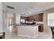 Open concept kitchen with dark wood cabinets, stainless steel refrigerator, and white tile floors at 10328 Celtic Ash Dr, Ruskin, FL 33573