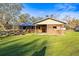 Horse barn featuring wooden stalls and a covered area, set on a green lawn with trees in the background at 10946 Gun Dog Way, Lithia, FL 33547