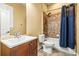 Bathroom featuring shower/tub with blue curtain, tile surround, brown vanity, and updated sink at 10946 Gun Dog Way, Lithia, FL 33547