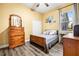 Cozy bedroom features wooden floors, a matching dresser and end table, and a comfortable bed at 10946 Gun Dog Way, Lithia, FL 33547