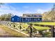 Charming blue farmhouse with a well-manicured lawn and a rustic wooden fence at 10946 Gun Dog Way, Lithia, FL 33547