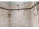 Close up of the shower's tiled walls, decorative strip, and shower head for a spa-like experience at 10946 Gun Dog Way, Lithia, FL 33547