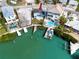 An aerial view showcases a waterfront property with a private dock and a cozy blue home at 14050 W Parsley Dr, Madeira Beach, FL 33708