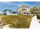 Spacious backyard featuring a quaint blue house with a lush lawn and a neighboring yellow house with balconies and a pool at 14050 W Parsley Dr, Madeira Beach, FL 33708