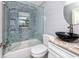 A bathroom with a black vessel sink and shower with decorative rock-look tile at 14050 W Parsley Dr, Madeira Beach, FL 33708