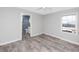 An empty bedroom with wood-look tile flooring features a ceiling fan and an adjacent bathroom at 14050 W Parsley Dr, Madeira Beach, FL 33708
