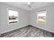 This bedroom features gray wood-look floors, two windows that provide ample natural light, and a modern ceiling fan at 14050 W Parsley Dr, Madeira Beach, FL 33708