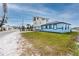 The home has a light blue exterior and sits on a lush green lawn with waterfront views at 14050 W Parsley Dr, Madeira Beach, FL 33708