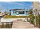 This property has a waterfront view with a wooden dock and light blue exterior with fresh landscaping at 14050 W Parsley Dr, Madeira Beach, FL 33708